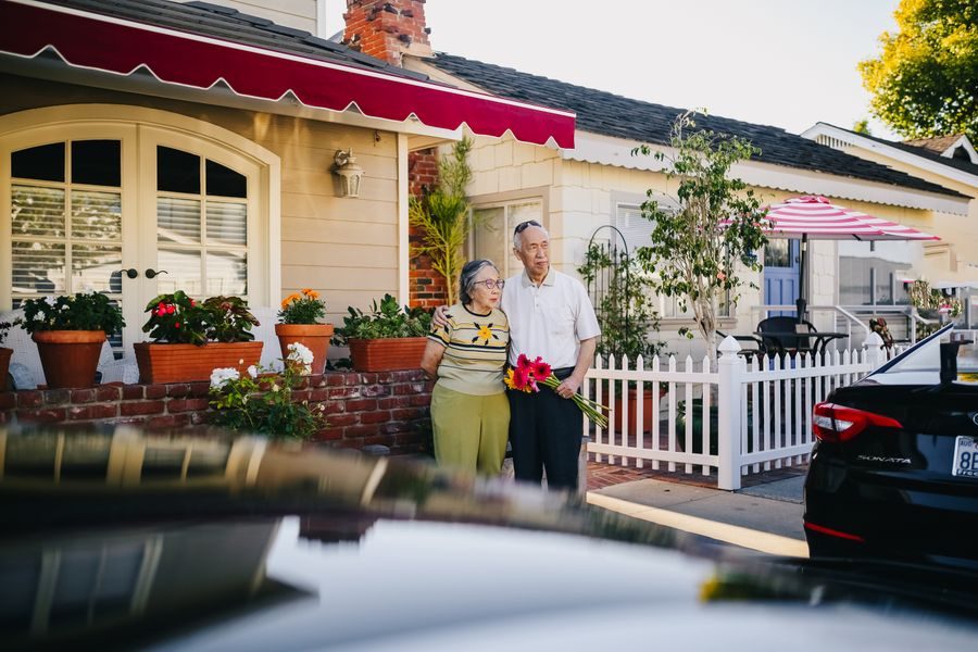 An older couple outside the front of their home