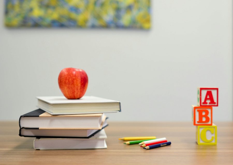 An apple on a stack of books with alphabet blocks